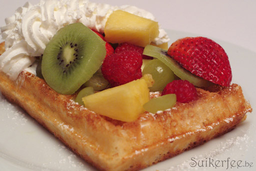 Verse brusselse wafel met bloemsuiker, slagroom, aardbeien, ananas, druiven, frambozen, kiwi en appel.